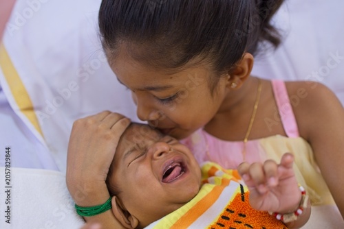 Sister comforting baby during a moment of distress in a living room setting