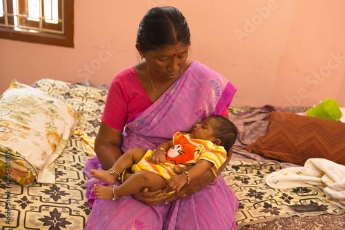 Woman holds baby in colorful room during daytime in a quiet home setting