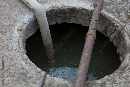 Photography The process of pumping dirty water or a septic tank through an open concrete manhole using a special flexible hose