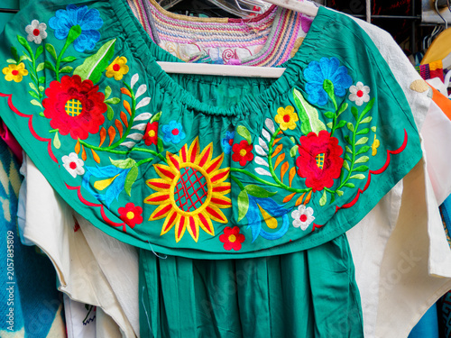Obraz na płótnie A green peasant blouse with an embroidered floral design for sale in a street ma