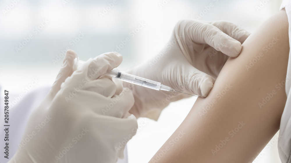 Fototapeta premium Healthcare professional administering vaccine injection into patient arm using sterile syringe and medical gloves.