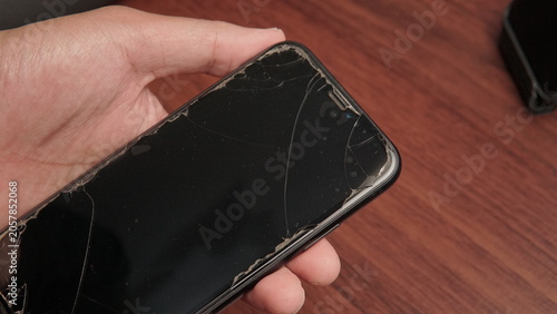Foto Holding cracked phone screen tempered glass with wooden background