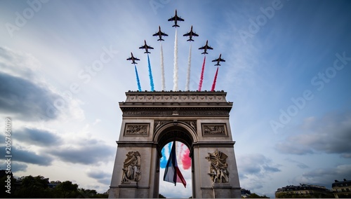 French military jets fly in precise formation trailing red, white and blue smoke over the Arc de Triomphe during Bastille Day celebrations, evoking national pride and patriotic ceremony in Paris.
