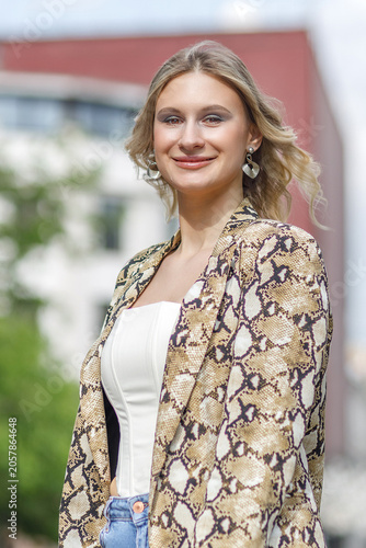 Portrait of a beautiful young blonde in the city center. The poses for photographs.