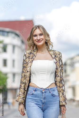 Portrait of a beautiful young blonde in the city center. The poses for photographs.