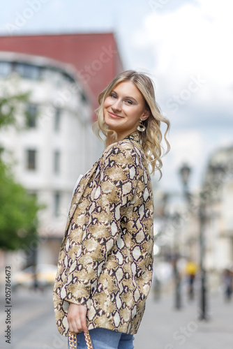 Portrait of a beautiful young blonde in the city center. The poses for photographs.