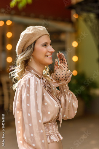 Portrait of a young blonde woman in a vintage pastel-colored outfit and a beret in the city center. Retro style.