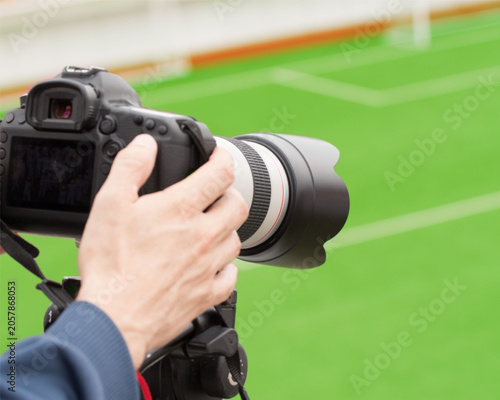 Photography Photographer holding camera with telephoto lens on green field
