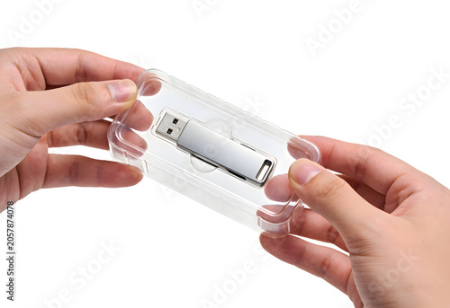Hand holding clear plastic case with a USB flash drive, close-up of electronic storage device, portable computer component, modern data transfer equipment, technology accessory
