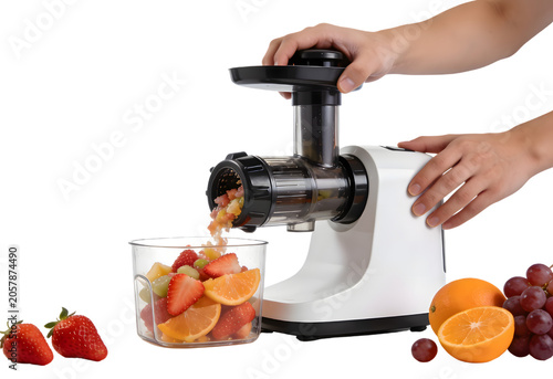 Close-up of a person using a home orange fruit juicer to make fresh juice from cut fruits with a glass bowl filled with sliced strawberries, oranges, and other fresh fruits on a white background