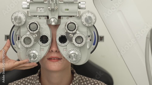 A positive female patient undergoes a professional vision check and refraction test using advanced ophthalmic equipment. This high-value commercial stock imagery represents preventative healthcare, pr