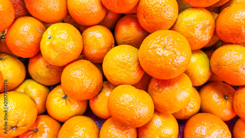A close-up view of a large pile of fresh, bright orange tangerines on display at a market.