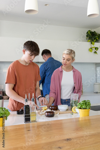 African American family preparing meal on home kitchen island using chef's knife and halved lemons