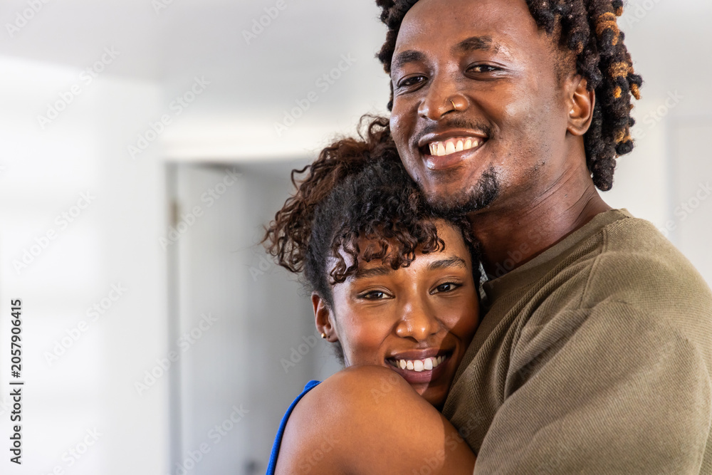 Obraz premium African American couple embracing, smiling at home, man with nose ring, woman showing stud earrings