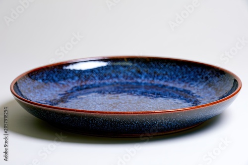 Deep blue glazed ceramic bowl with rustic brown rim