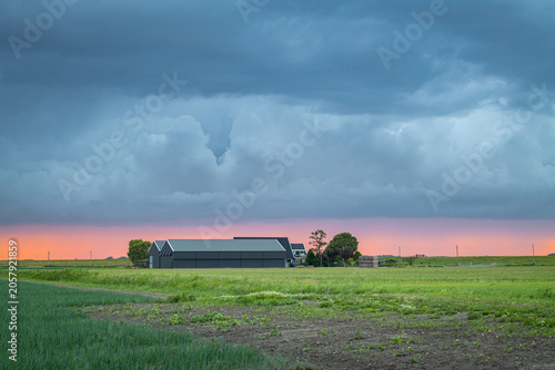 Vászonkép Stormy sunset over rural farm with barn and dramatic clouds on open prairie land