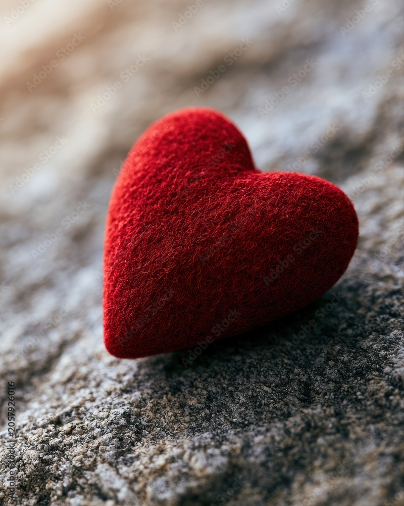 Obraz premium red heart placed on stone surface, love yourself first concept, warm cinematic lighting