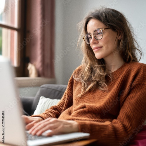 Woman working remotely using laptop, reviewing content at home