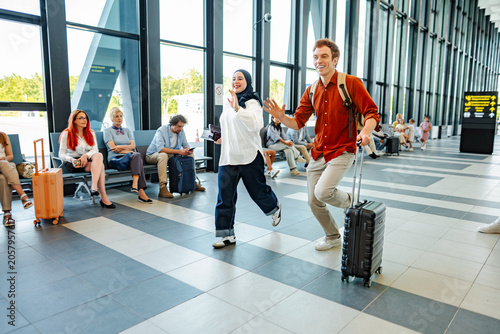 Bild auf Leinwand Diverse couple rushing through airport terminal for departure