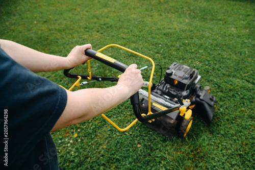 Konstfotografi young woman using black and yellow lawn mower for lawn mowing, green grass, sunn