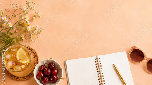 Summer journaling flat lay with iced herbal tea, cherries, notebook and copy space