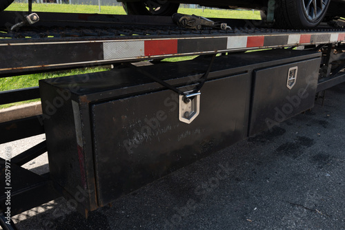 Fotografie Close-up of a black metal toolbox mounted under a flatbed trailer, secured with