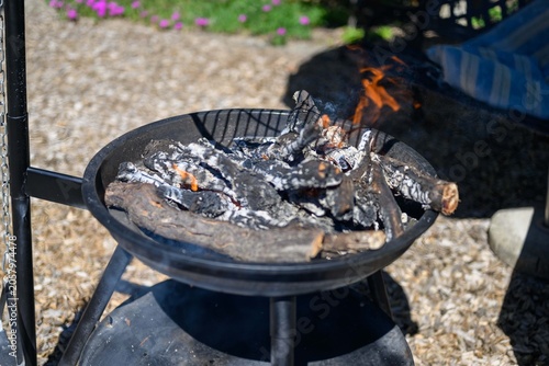 Feuerschale mit glühendem Brennholz im Freien