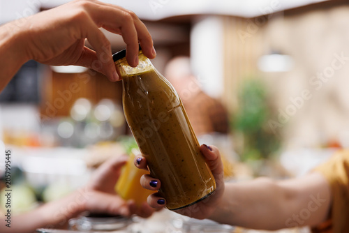 Fotografi Storekeeper offering woman shopping in zero waste grocery store organic healthy natural juice, blurry background
