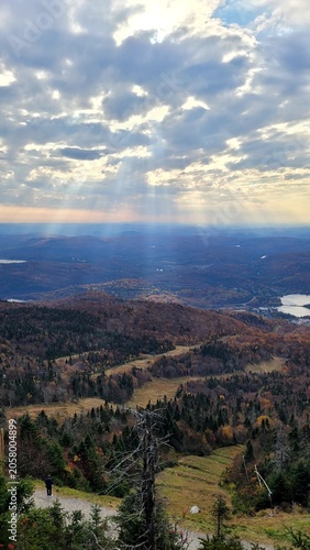 Breathtaking mountain view of autumn forest valley with sun rays breaking through dramatic clouds