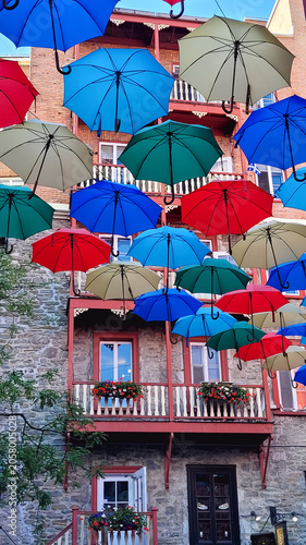 Colorful umbrellas floating in the air against a historic building facade in Quebec City