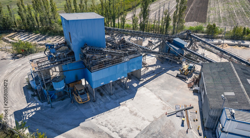 Close up aerial view of industrial aggregate processing facility and conveyor infrastructure in Southern France