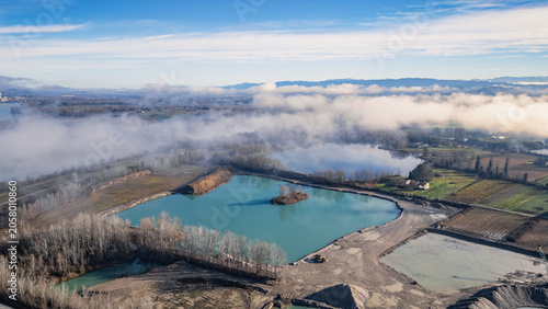 Morning mist drifting over quarry lake and aggregate extraction site in the Rhône Valley, France