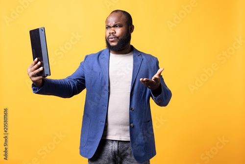 Foto Offended man fighting with friends after receiving affronts during teleconference meeting using tablet, studio background, rude person in disagreement with mates during video call on portable device