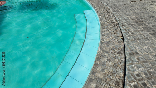 Clear blue swimming pool with textured stone patio and inviting water surface reflecting sunlight