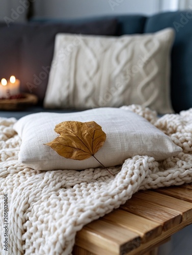 Cozy autumn scene with a dried maple leaf resting on a pillow