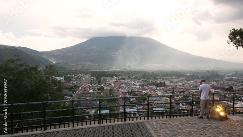 A photographer tries to capture the landscape from the viewpoint of Cerro de la Cruz, the city of Antigua Guatemala stretches peacefully beneath the towering silhouette of Volcán de Agua. The volcano 