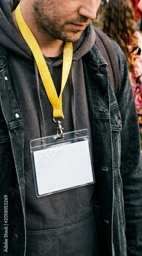 Man wearing a blank ID badge card mockup with a yellow lanyard at an outdoor event or music festival