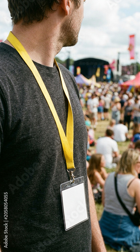 Man wearing a blank ID badge card mockup with a yellow lanyard at an outdoor event or music festival