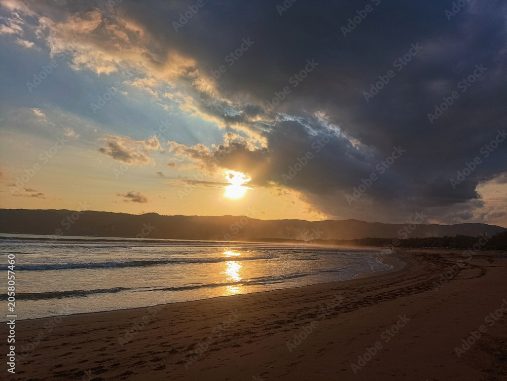 Obraz premium Dramatic Sunset Over Tropical Beach with Dark Storm Clouds