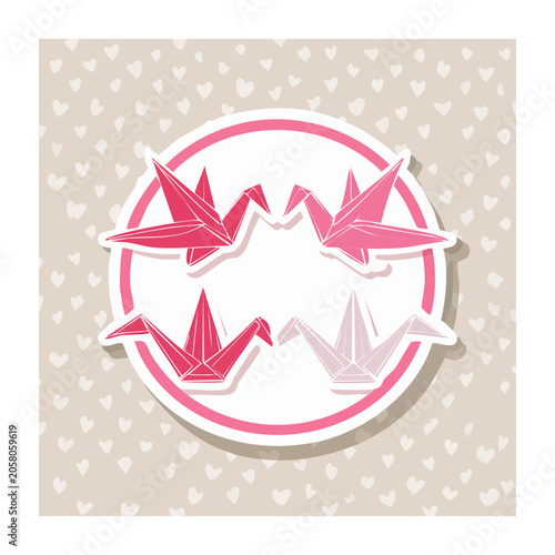 Pink origami cranes in circular frame with heart pattern background