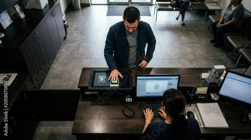 Man Uses Fingerprint Scanner at Reception Desk for Identification