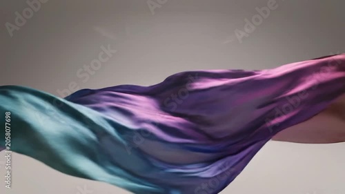 Flowing teal and purple silk fabric on gray background.
