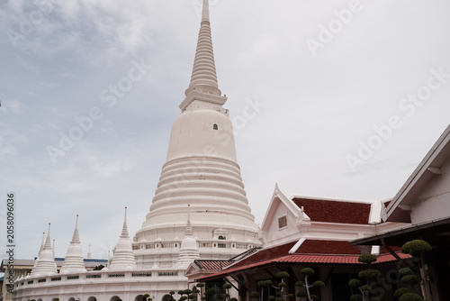 Foto Grand white bell-shaped pagoda surrounded by smaller chedis and traditional Thai temple buildings