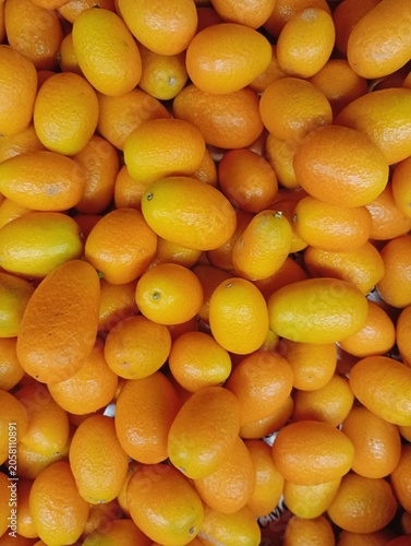 Foto Textured background of a dense pile of fresh ripe orange kumquat fruits