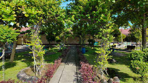 Lush garden pathway framed by green foliage and vibrant flowers leading towards a tranquil space