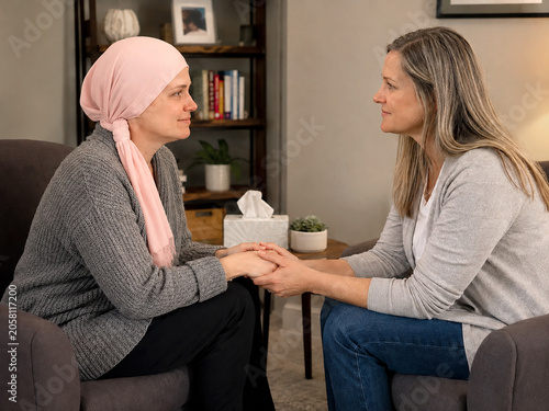 Compassionate Friend Supporting Woman Wearing Pink Cancer Head Scarf
Two women sit facing each other and hold hands in a heartfelt moment of support. 