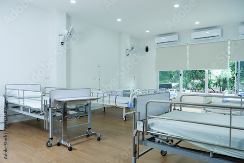 Clean, bright hospital room showcases multiple beds with air conditioning and ceiling fans?promoting serene and comfortable environment for patient recovery within modern medical setting.