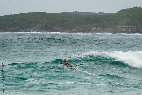 Female surfer paddling out into ocean waves