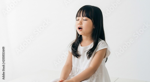明るく柔らかな光が降り注ぐシンプルなスタジオで無邪気な少女が純粋な感情を込め歌声を響かせ目を閉じ口を大きく開けて表現する瞬間白い背景がその生き生きとした表情と内面の輝きを際立たせる. AI Generated
