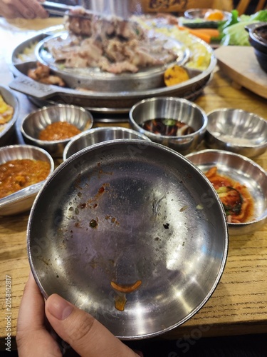 Korean BBQ dining scene in Seoul — empty metal plate held after enjoying grilled meat with side